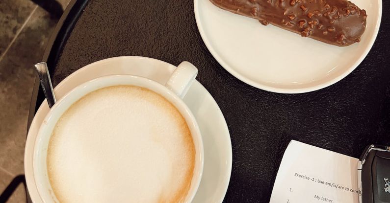 Food Processors - A coffee and a pastry on a table next to a notebook